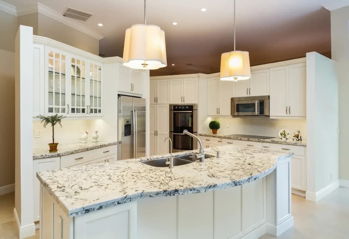 A bright kitchen with white refinished cabinets, a large island and pendant lights